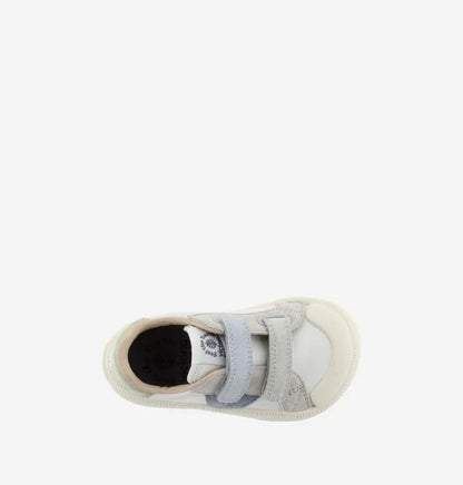 Vista superior de uma sapatilha infantil barefoot branca com detalhes azuis e cinzentos, mostrando a biqueira larga e os fechos de velcro.