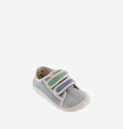 Sapatilha infantil de lona azul clara e cinzenta, com duas tiras de velcro em tons de verde e azul, vista de perfil em fundo branco.