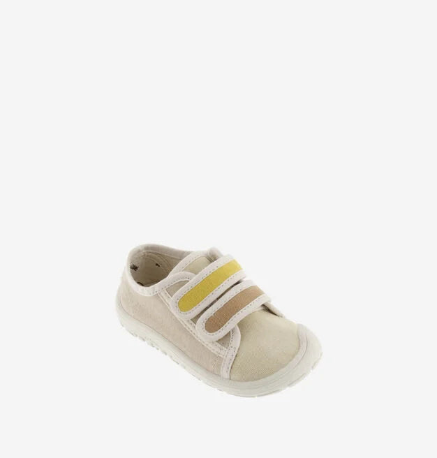 Sapatilha infantil da marca Victoria em lona bege, vista de um ângulo superior, com fechos de velcro em tons de amarelo e castanho claro.
