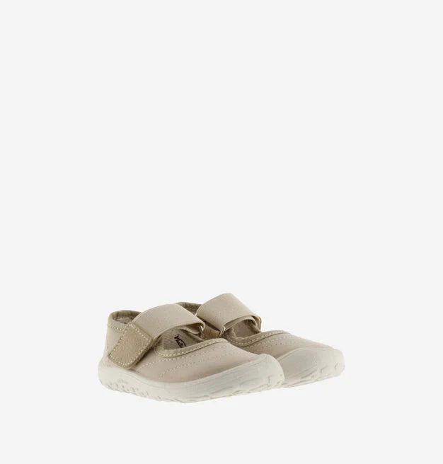Par de sapatilhas bege de criança estilo bailarina com fecho de velcro, apresentadas ligeiramente inclinadas.