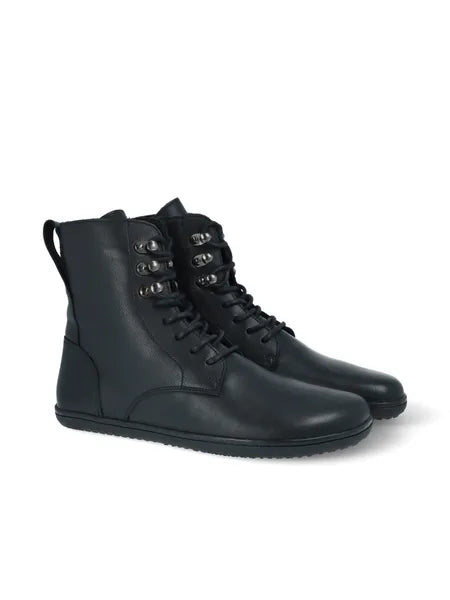 Par de botas de atacadores pretas, cano alto, estilo militar/coturno, com sola fina, em fundo branco.